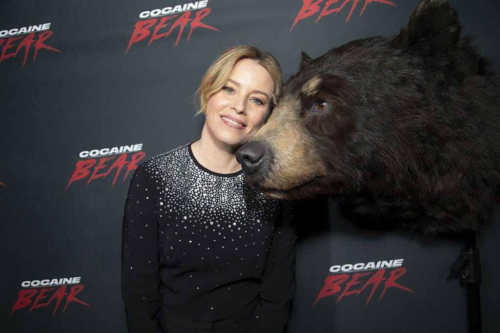 elizabeth banks junto a la cara de un oso